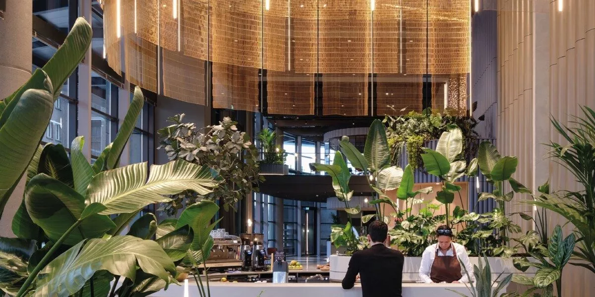 Een foto van een lobby met planten met daar achter een scherm dat ontwikkeld is door het bedrijf Twentinox